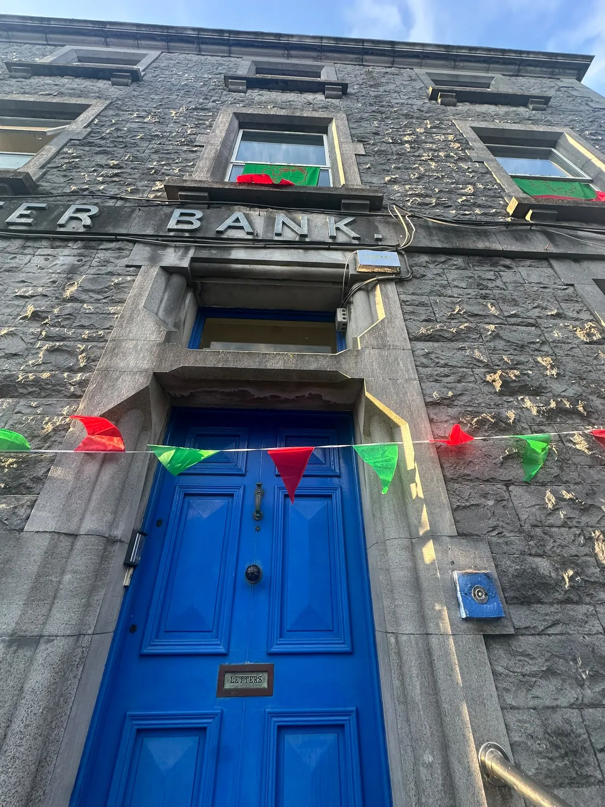 The blue front door of the Nexus under the old bank sign