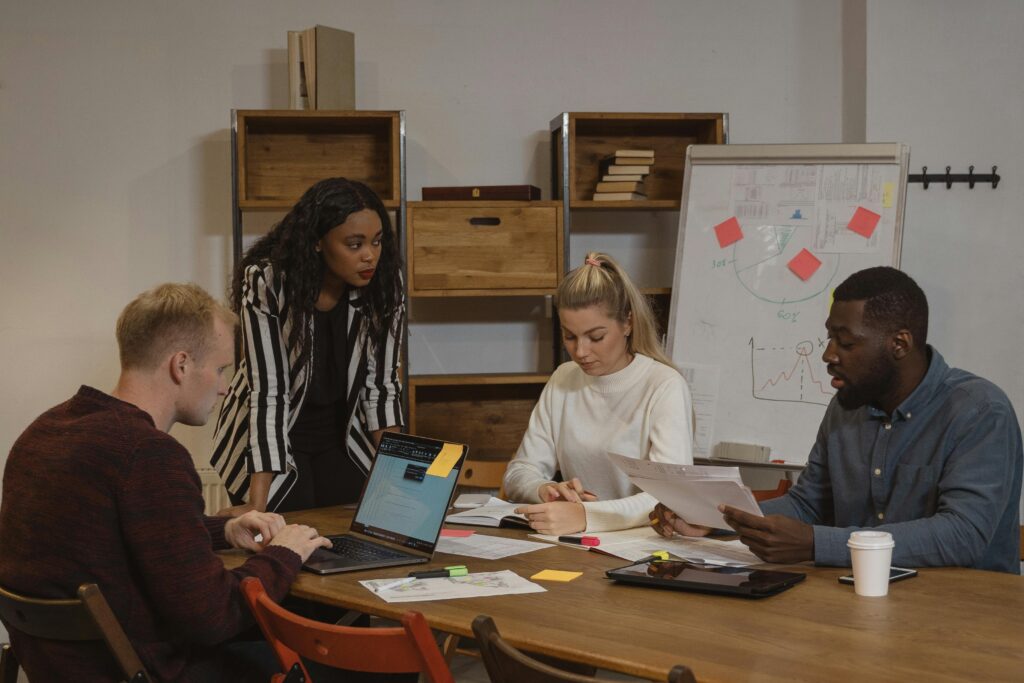 A multicultural team collaborating in a modern office setting with laptops and graphs.