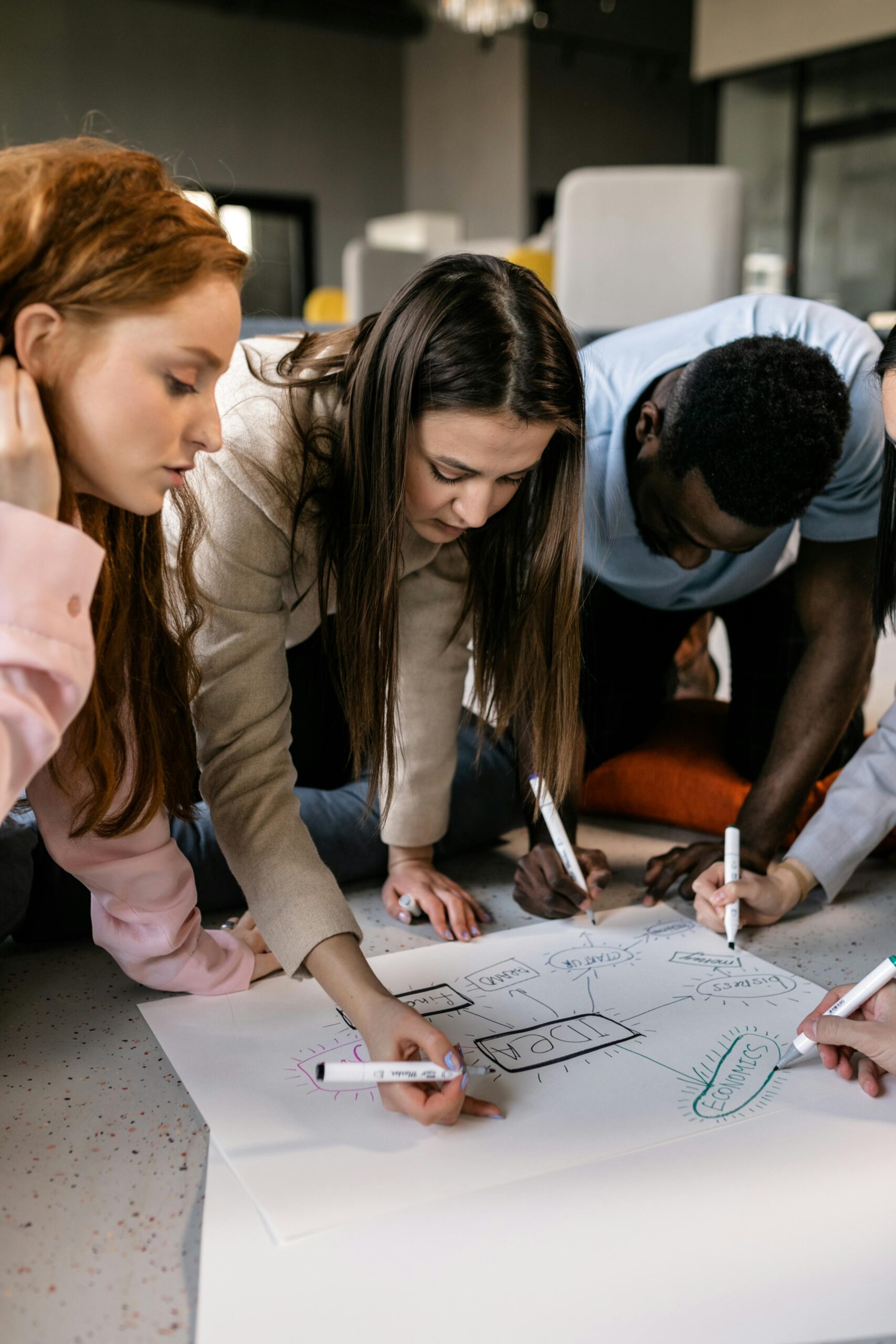 Colleagues gather around a paper, brainstorming creative ideas for a small business strategy.