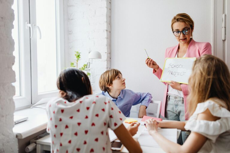 A teacher engaging with students in a classroom setting for a school project discussion.